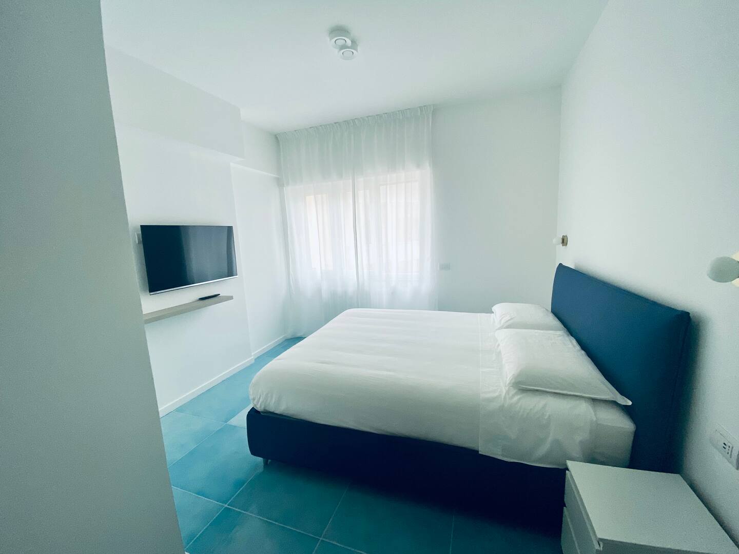 A stylish and bright suite at Il Capo Suites with a comfortable bed and modern design.